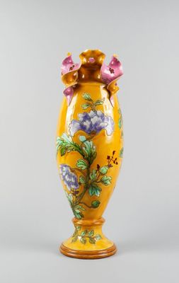 yellow vase with purple flowers on it sitting on a white surface