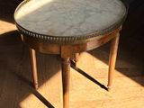 une petite table au plateau en marbre posée sur un parquet en bois massif