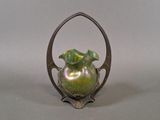 a green vase sitting on top of a metal stand