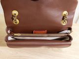 brown leather handbag with gold hardwares on a wooden table