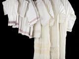 several white shirts hanging on a clothes rack on a black background