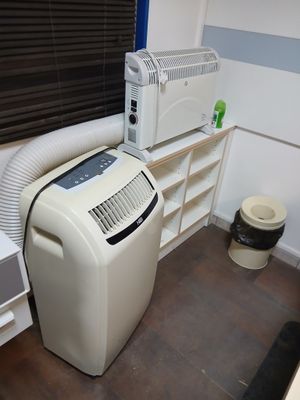 un climatiseur blanc placé à côté d'une fenêtre dans une pièce