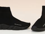 a pair of black sneakers with black soles on a white surface