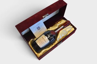 a bottle of liquor in a wooden box with a gold ribbon