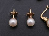 two pairs of pearl earrings and a pair of gold earrings on a black surface