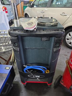 une poubelle noire équipée d'un tuyau, dans un garage