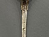 silver spoon sitting on top of a table next to a white wall