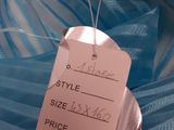 a price tag on a blue dress that is on a bed