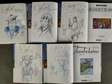 several books with drawings of people on them sitting on a table