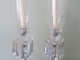 pair of clear glass candlesticks on a table with a white wall in the background