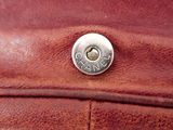the back of a brown leather purse with a metal button on it