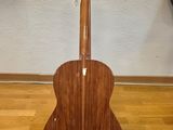 an acoustic guitar sits on a stand on a hard wood floor