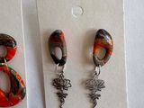 three pairs of earrings are displayed on a white surface