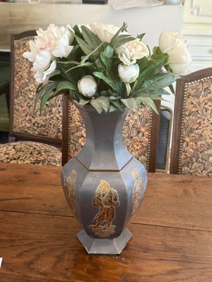 a vase of flowers on a table with chairs in the background