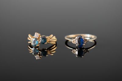 deux bagues en or ornées de pierres bleues et de diamants sur un fond noir