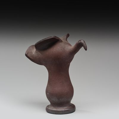 un vieux vase marron surmonté d'un oiseau