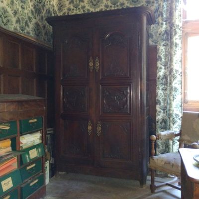 une grande armoire en bois dans une pièce au papier peint à motifs floraux