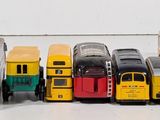 a lot of toy cars and buses lined up on a table