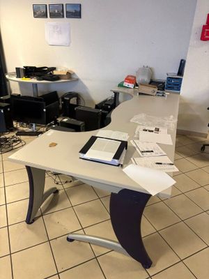 une table blanche sur laquelle est posé un ordinateur portable, dans une pièce