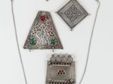 three pieces of silver jewelry are displayed on a white surface