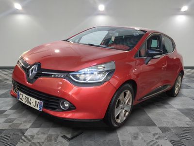 une voiture rouge est garée dans une pièce au sol en damier