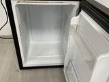 a small black and white refrigerator in the corner of a room