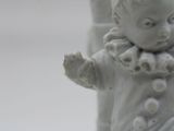 a white statue of a child with a clown ' s hat on