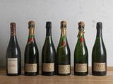 six bouteilles de champagne alignées les unes à côté des autres sur une table en bois