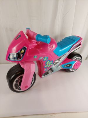 une moto jouet rose et bleue posée sur une table blanche