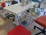 many sewing machines in a large room with red stools