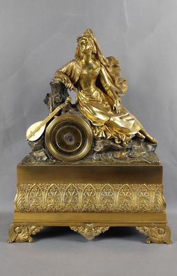 Pendule en bronze doré, représentant une femme assise, vêtue…
