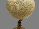 a small globe on a wooden stand with a gray background