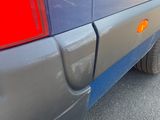 the rear end of a blue van with a red tail light on