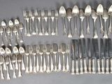 un grand nombre de cuillères et de fourchettes en argent disposées sur une table