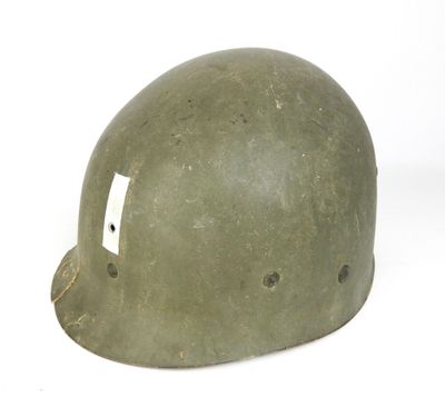 un vieux casque vert troué posé sur une surface blanche