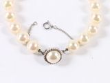 a close up of a bracelet with pearls on a white background