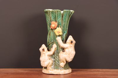 un vase en céramique orné de deux ours et contenant une fleur