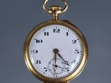 a close up of a gold pocket watch on a gray background