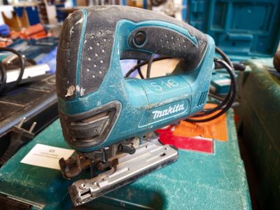 a corded jig saw sitting on top of a green box