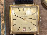 une montre en or posée à côté d'un livre et d'une montre sur une table