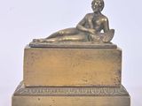 bronze statue of a woman reclining on a box on a white background