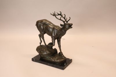sculpture en bronze représentant un cerf debout sur un rocher, sur fond blanc