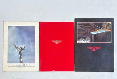 Trois brochures Rolls-Royce sont alignées sur une surface blanche