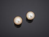 a pair of pearl earrings on a black surface