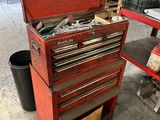une caisse à outils rouge, sur laquelle sont posés des outils, dans un garage