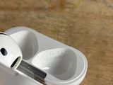 someone is holding a pair of airpods that are sitting on a table