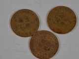 three coins sitting on top of a white surface next to each other