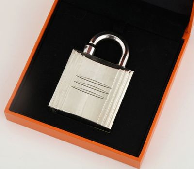a silver padlock in a black box on a white surface