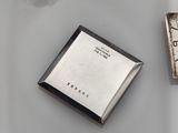 a silver clock and a book on a table