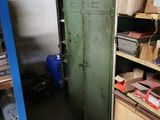 a green locker in the middle of a room filled with boxes